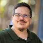 Man wearing glasses smiles at the camera