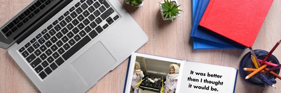 Book sits next to a laptop with a photo of two kids in space suits. The opposite side of the page reads: "It was better than I thought it would be."