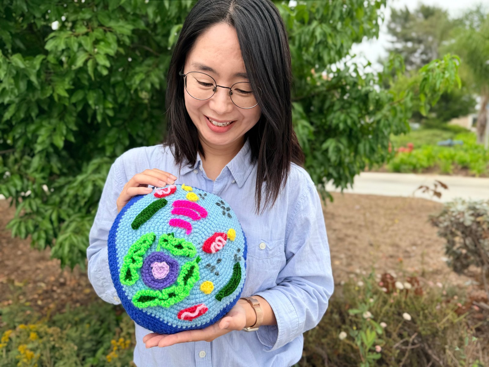 Dr. Chloe Kim holds a colorful crocheted representation of a cell. 